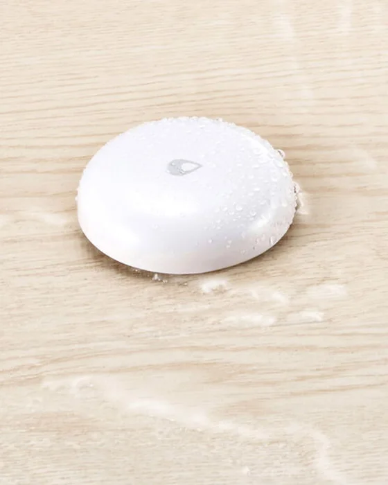 Sensor de fuga de agua Aqara detectando agua derramada sobre un piso de madera
