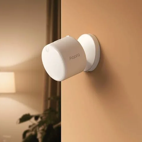 Sensor de presencia Aqara en la pared de un living con luz cálida